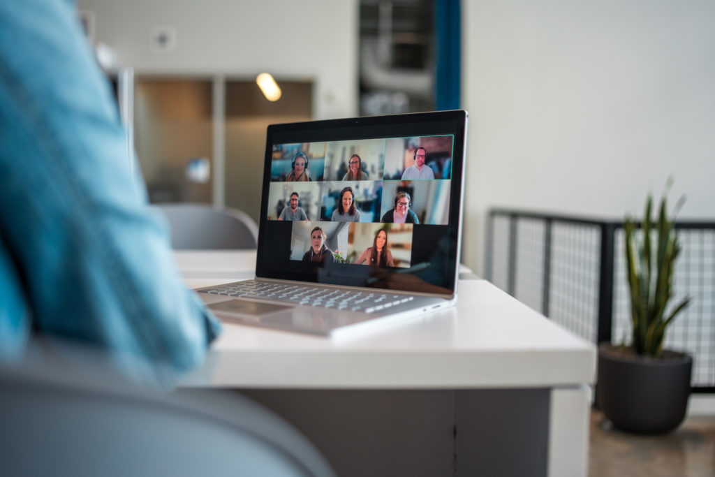 An attentive Hispanic businesswoman participates in a virtual conference call using a laptop in her streamlined modern office, symbolizing connectivity and professionalism.