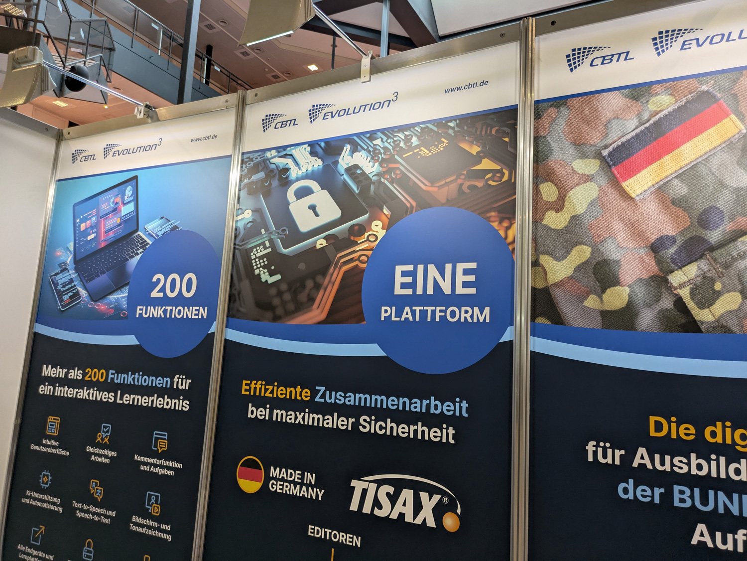 Rückwand des CBTL-Messestandes auf dem Ausbildungskongress der Bundeswehr 2025 mit Sicherheitszertifikaten und einer Übersicht der wichtigsten Funktionen der Autorensuite EVOLUTION³.