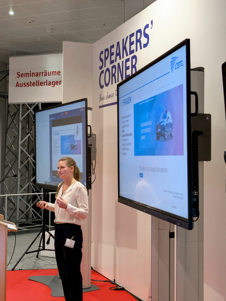 Referentin beim Ausbildungskongress der Bundeswehr 2025 während ihres Vortrags zu Critical Thinking, neben ihr ist der Präsentationsbildschirm mit den Folien sichtbar.